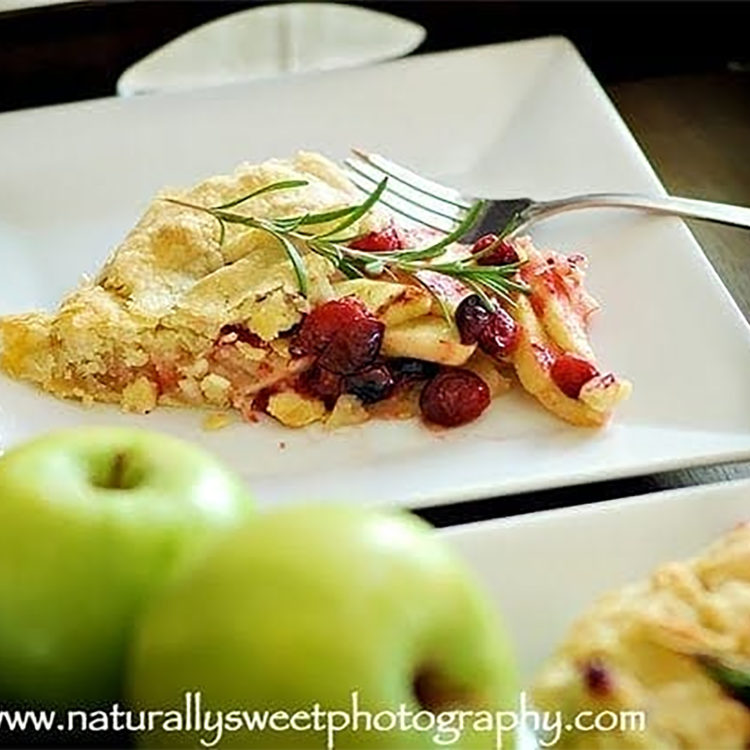 a slice of apple cranberry galette on a square white plate with a fork