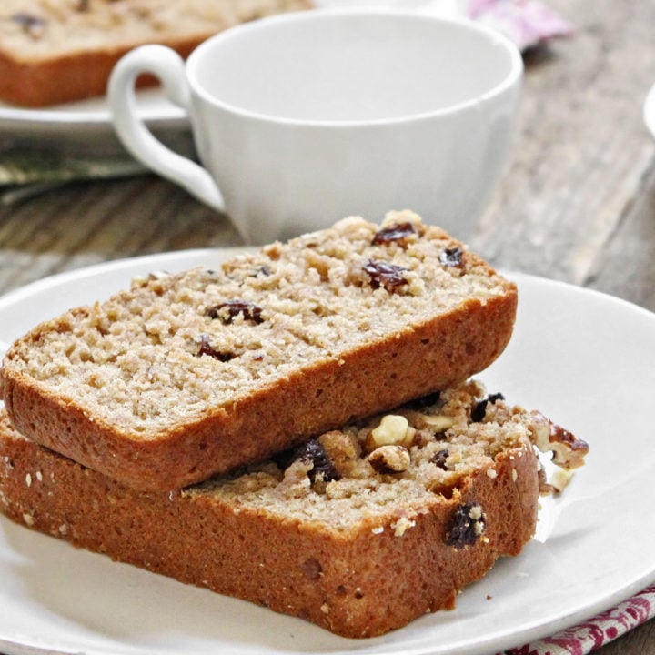 two slices of applesauce bread on a white plate next to a tea cup