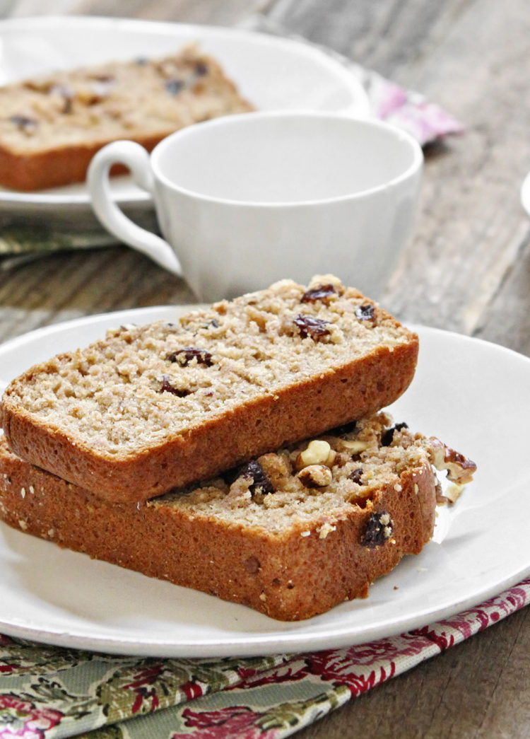 two slices of applesauce bread on a white plate next to a tea cup