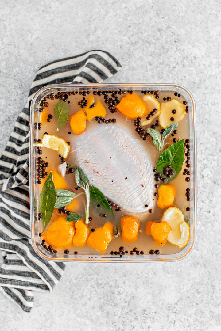 Overhead view of a raw turkey breast soaking in a container with brine ingredients before preparing this traeger smoked turkey recipe. 