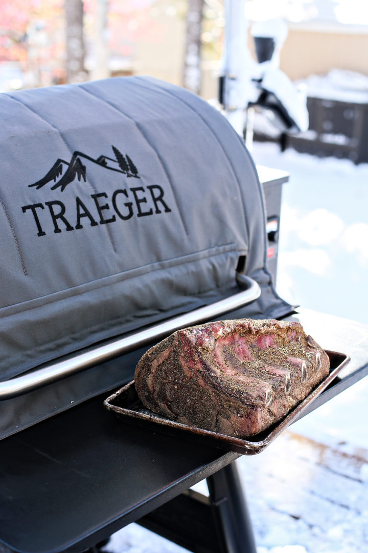 uncooked prime rib on a sheet pan next to a traeger grill before smoking