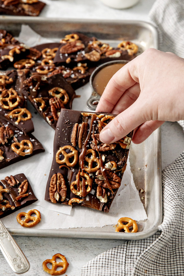 woman holding a piece of pretzel bark with caramel