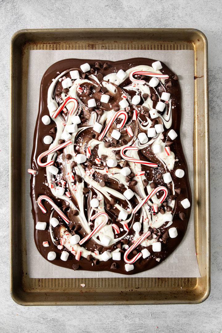 dark and white chocolate swirled and topped with candy canes, chocolate chips, and marshmallows to make candy cane bark