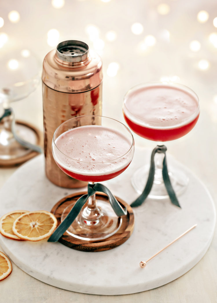 two coupe glasses filled with cranberry orange whiskey sour