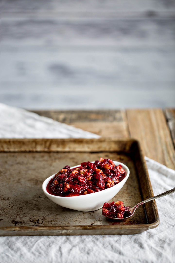 cranberry sauce with orange juice in white serving dish next to spoon