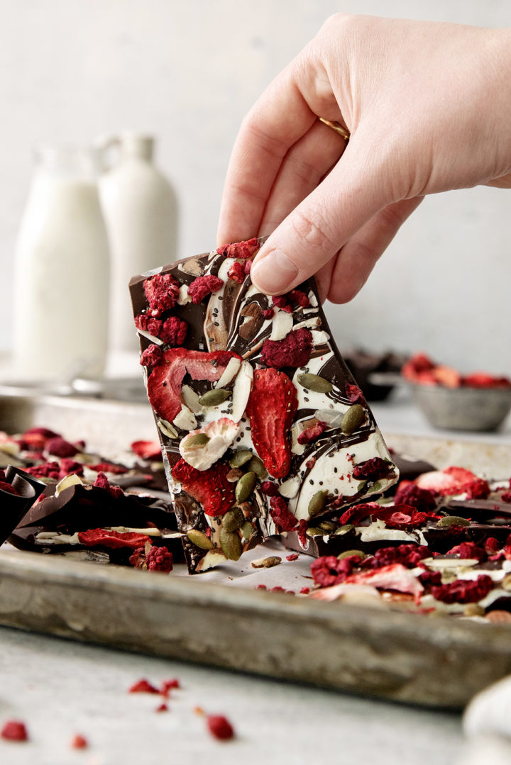 woman holding a piece of fruit and nut chocolate bark