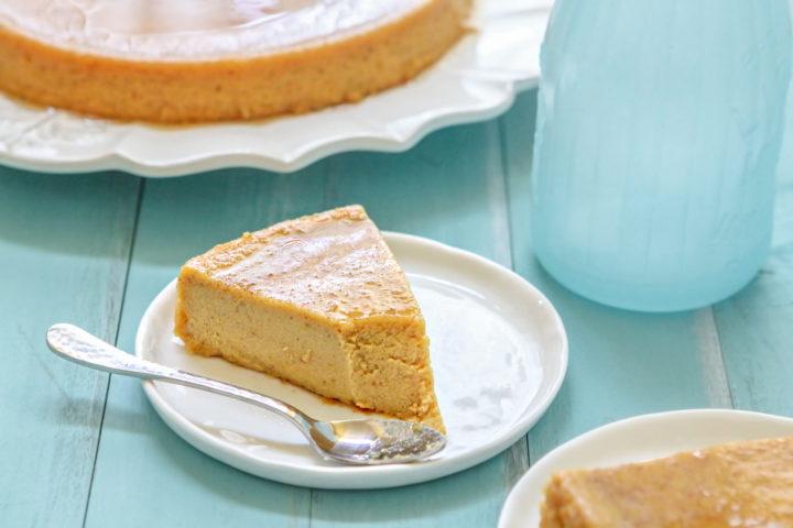 a white plate and spoon with a slice of pumpkin creme caramel with a bite taken out