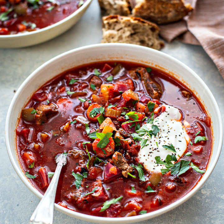 bowl of borscht with meat on a grey surface