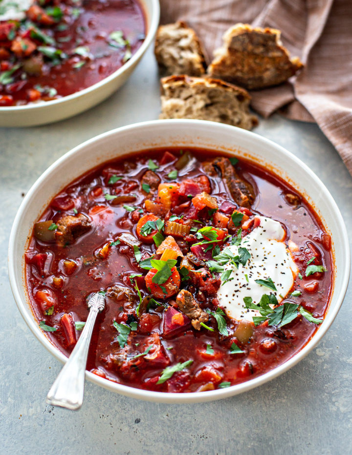 bowl of russian borscht with meat on a grey surface