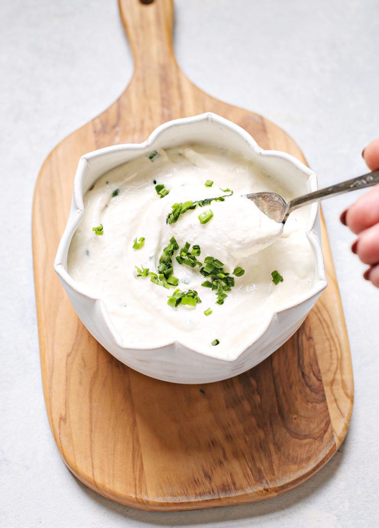 woman stirring a bowl of homemade horseradish sauce for prime rib