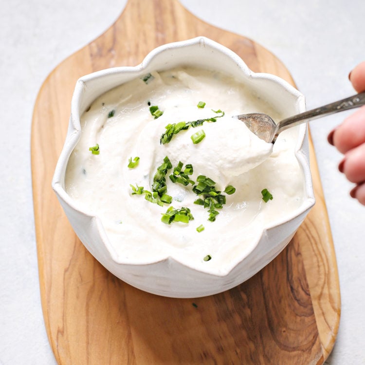 woman stirring a bowl of homemade horseradish sauce for prime rib