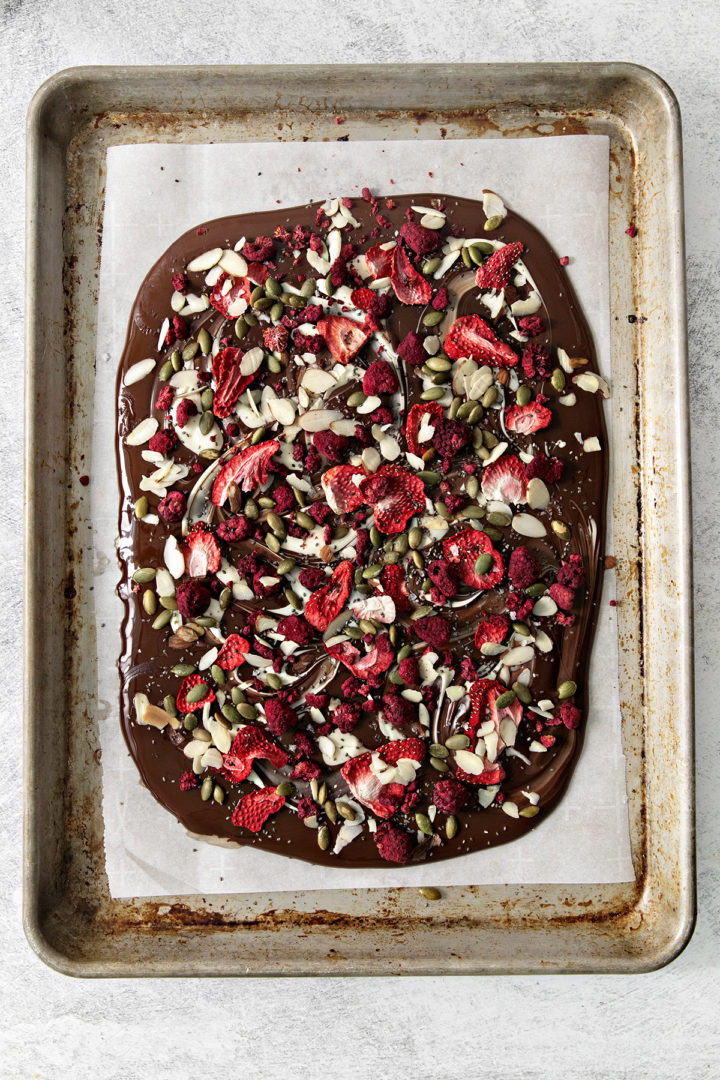 overhead photo of dark and white chocolate with dried fruits and nuts on it