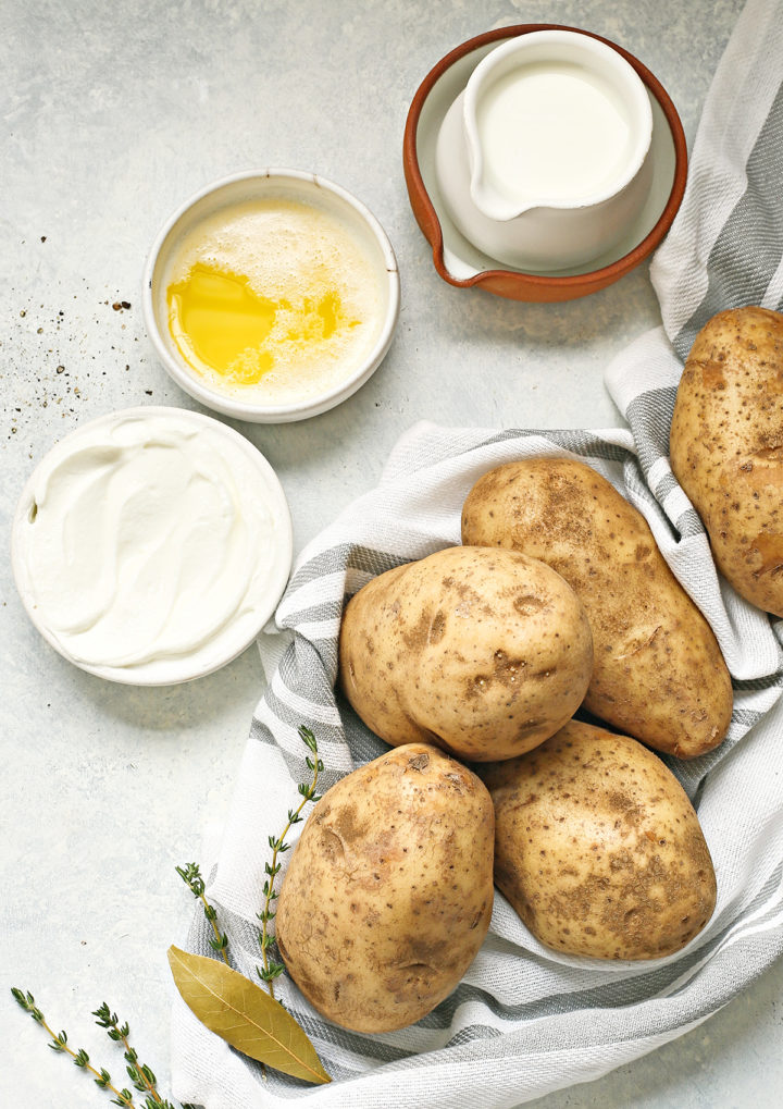 greek yogurt in a bowl next to butter, potatoes, and other ingredients to use in this greek yogurt mashed potato recipe