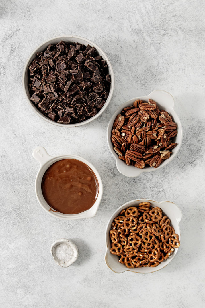 overhead photo of ingredients needed to make caramel pretzel bark in white bowls
