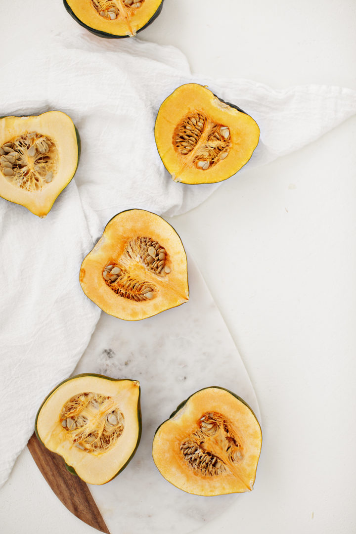 acorn squash halves on a white counter to make a stuffed squash recipe