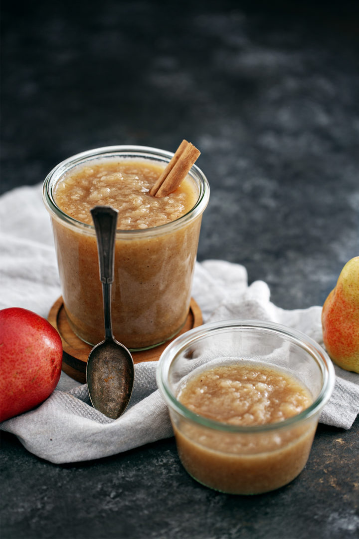 jars of homemade pear sauce with a spoon on a dark background