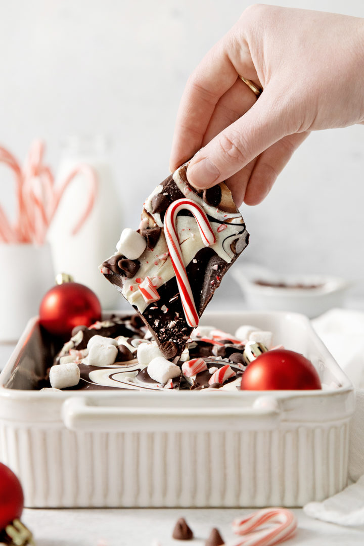 woman holding a piece of homemade chocolate peppermint bark