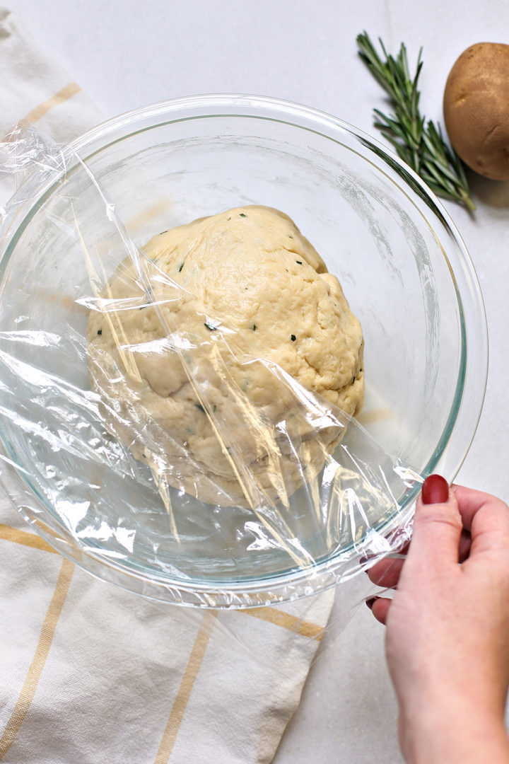 woman covering a boll of prepared dough for potato bread rolls