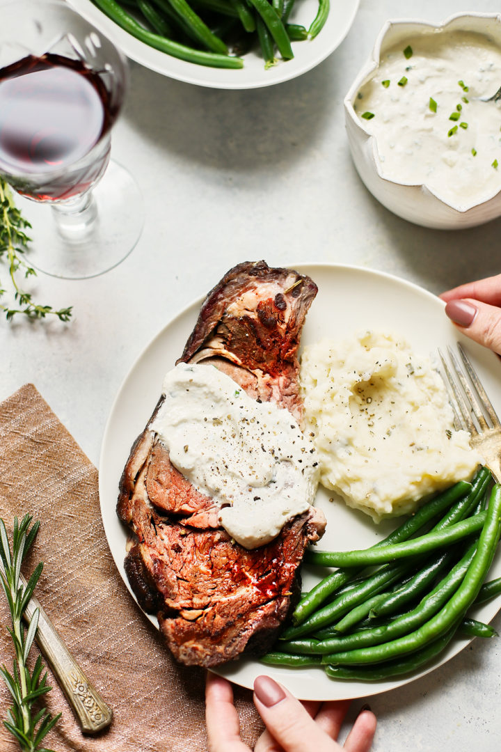 woman setting a plate of smoked prime rib on the table