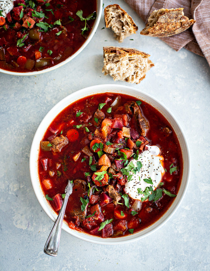 overhead shot of a bowl of russian borscht with meat and a dollop of sour cream
