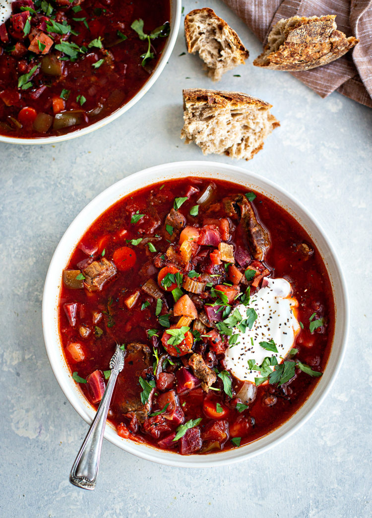 bowl of borscht with meat on a grey surface