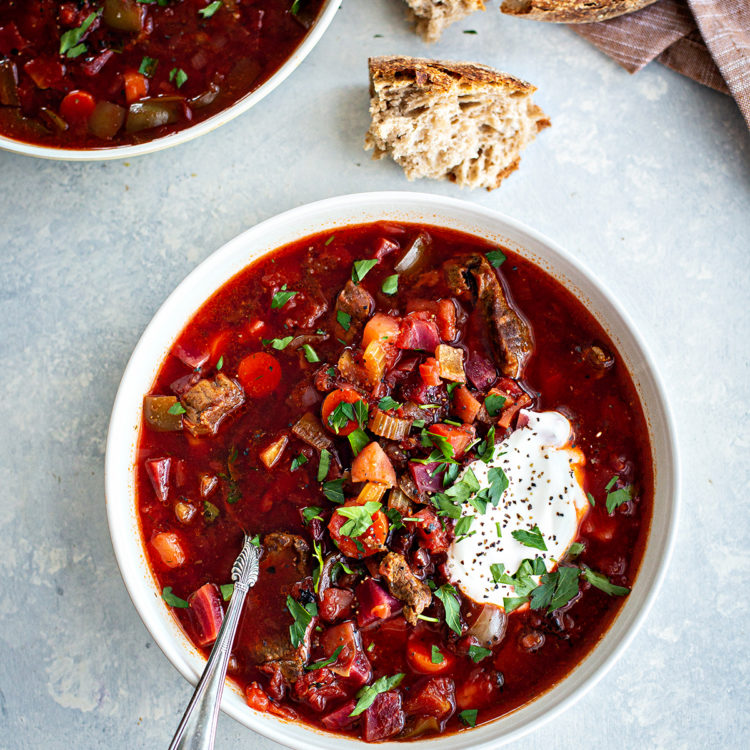 bowl of borscht with meat on a grey surface