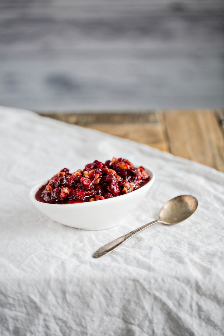 cranberry sauce with orange juice in white serving dish next to spoon