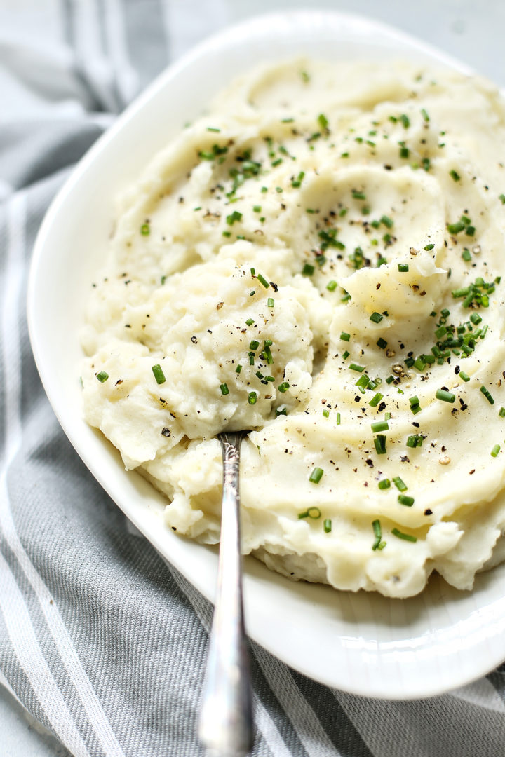 Greek yogurt mashed potatoes in a white serving bowl with a serving spoon