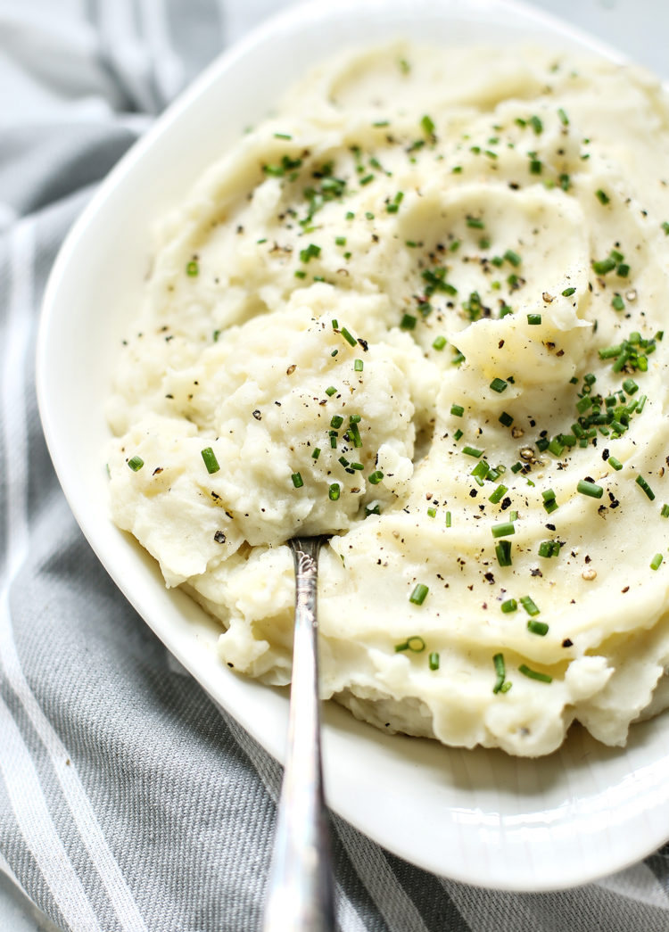 Greek yogurt mashed potatoes in a white serving bowl with a serving spoon