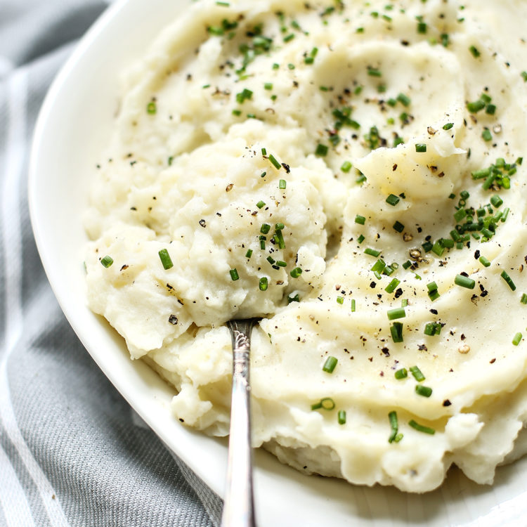 Greek yogurt mashed potatoes in a white serving bowl with a serving spoon