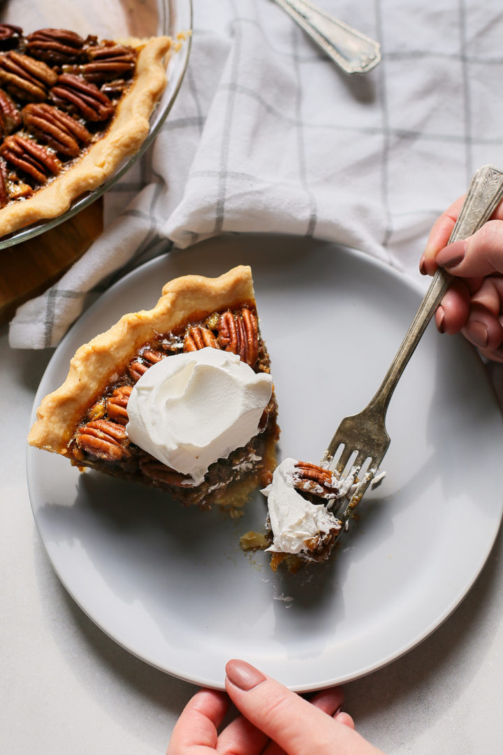 woman taking a bite of a slice of bourbon pecan pie