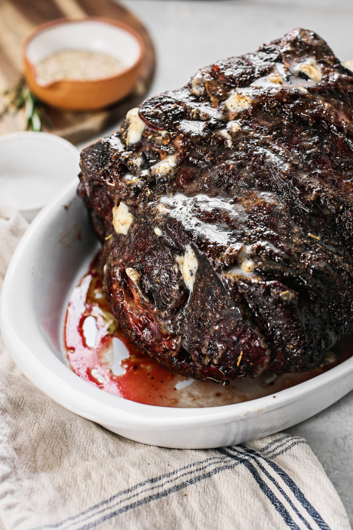 smoked prime rib in a white dish coated in butter after cooking on the traeger