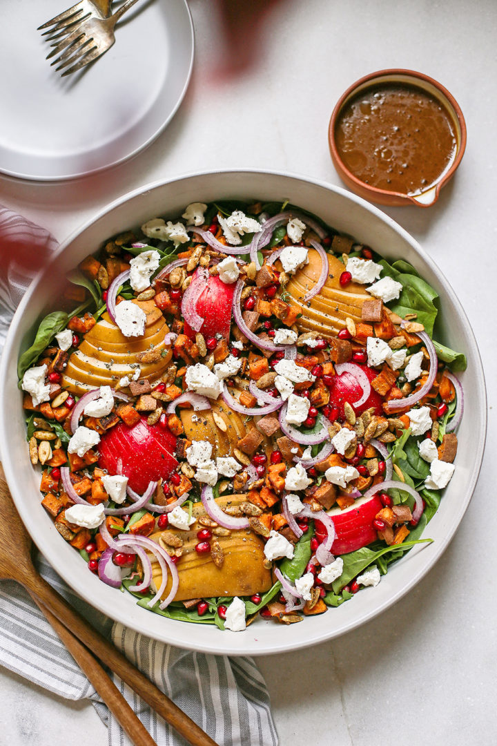 pear goat cheese salad in a serving bowl with wooden spoons