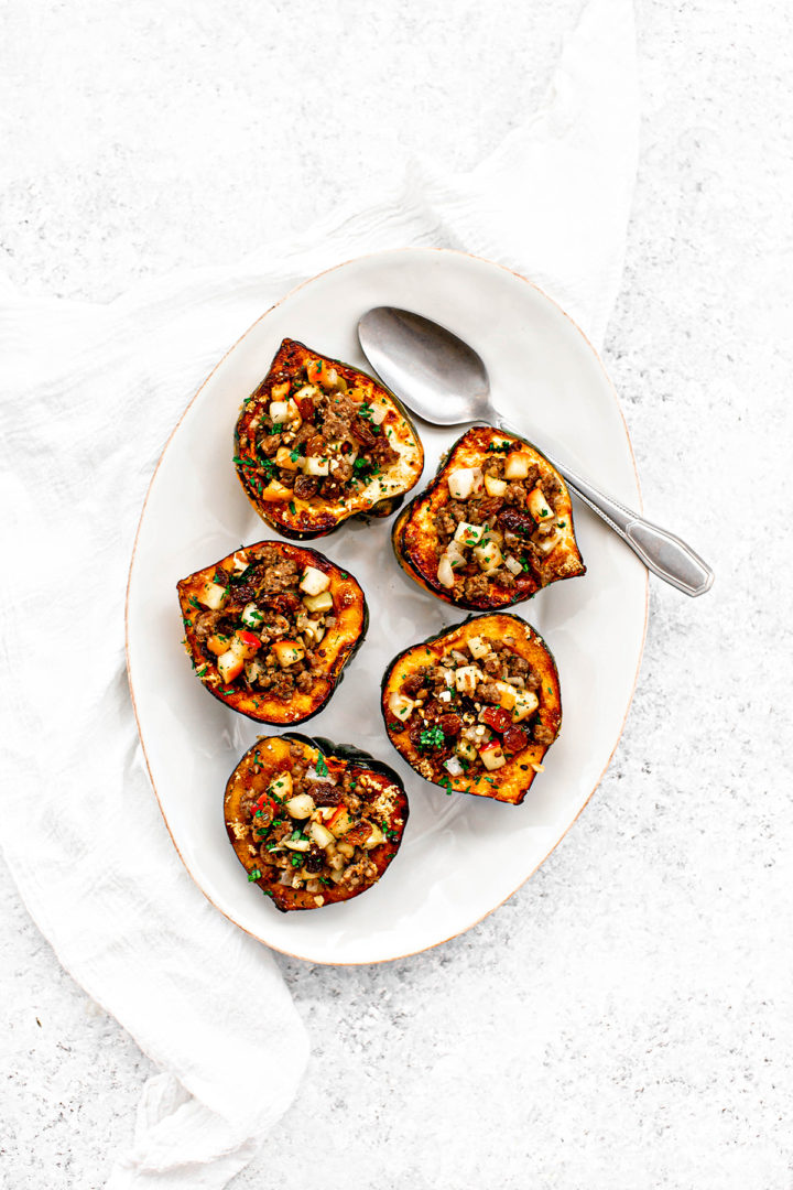 white platter with acorn stuffed squash with sausage and apple