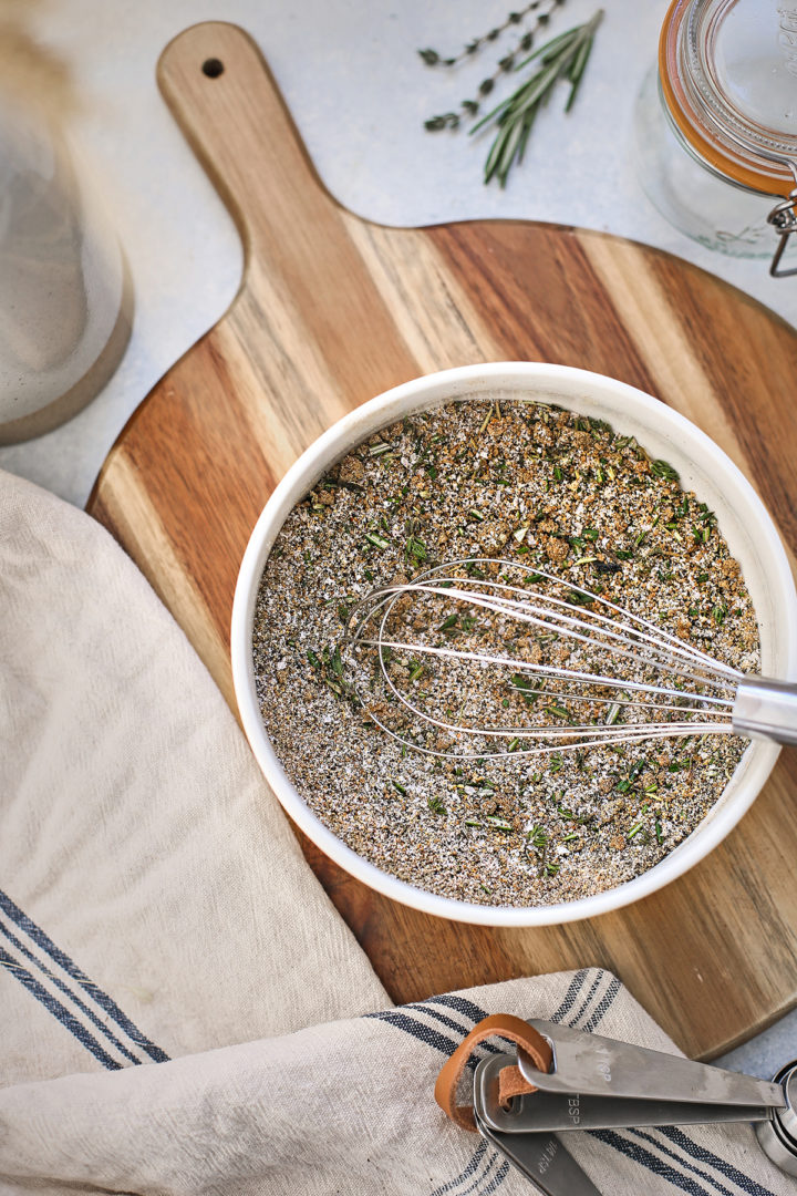 ingredients to make traeger prime rib - a bowl of rub on a cutting board with fresh herbs