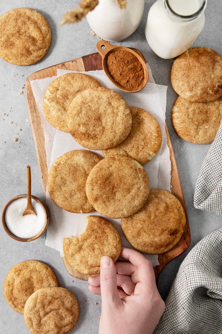 woman picking up a brown butter cookie off a cutting board