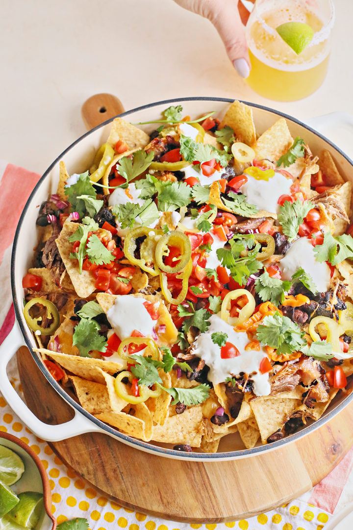 photo of pulled pork nachos next to a glass of beer