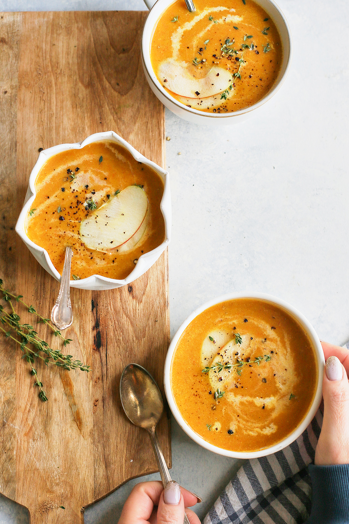 woman picking up a bowl of butternut squash soup and apple	