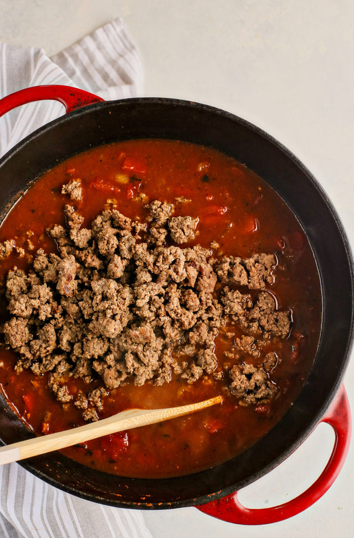 adding ground beef to a pot of kidney bean chili