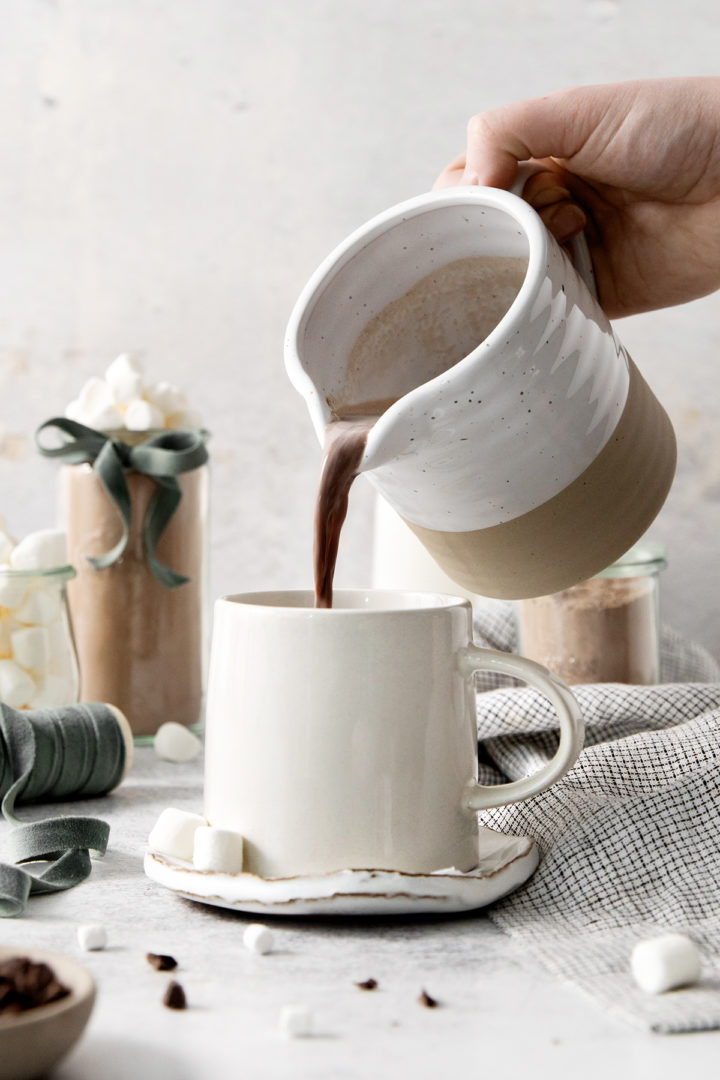 woman pouring a mug of prepared hot chocolate from this homemade hot cocoa mix