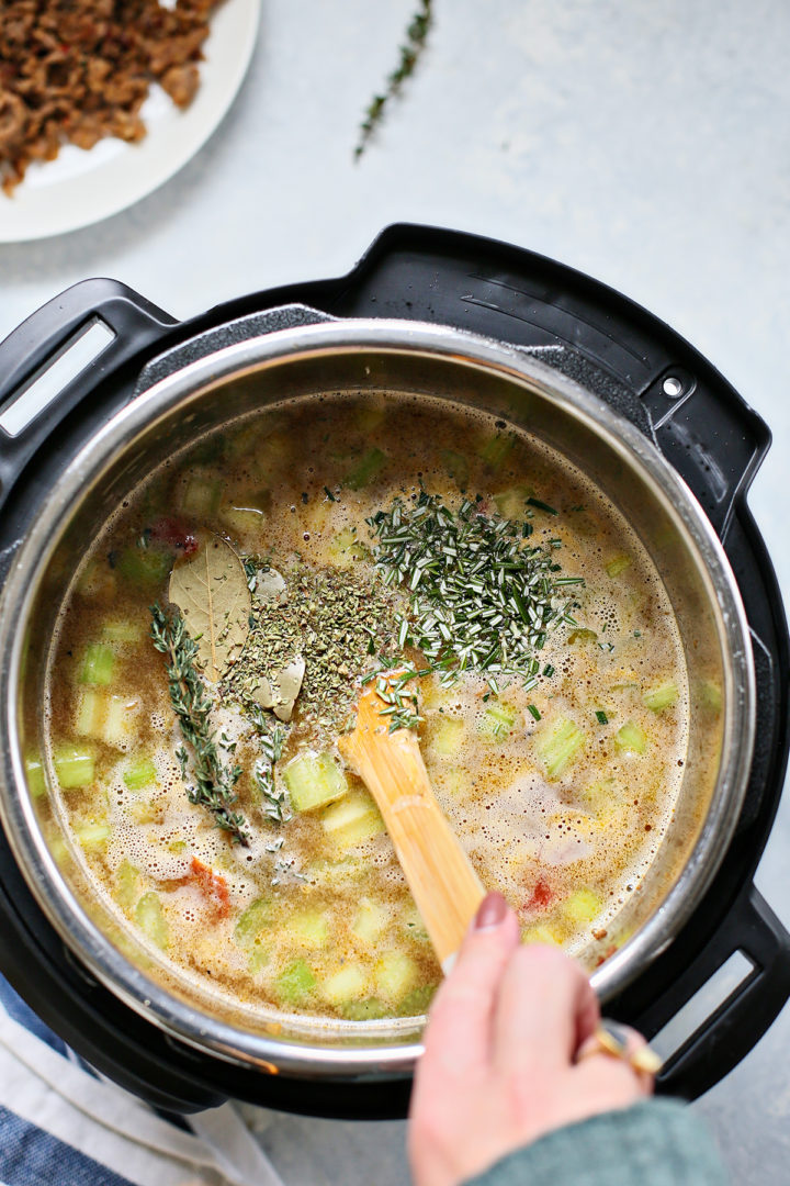 woman stirring herbs into easy instant pot lentil soup