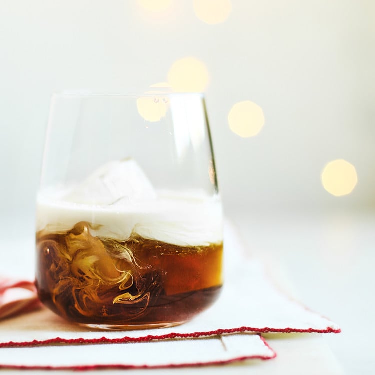 peppermint white russian in a glass with christmas lights in the background