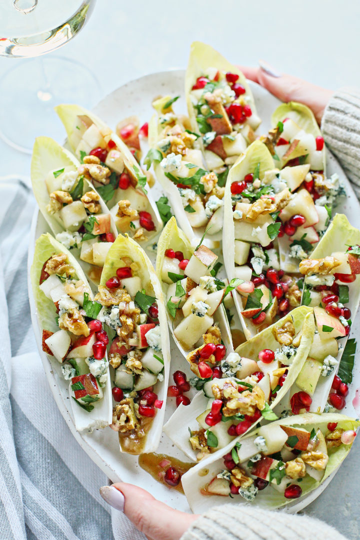 woman serving a platter of endive appetizers