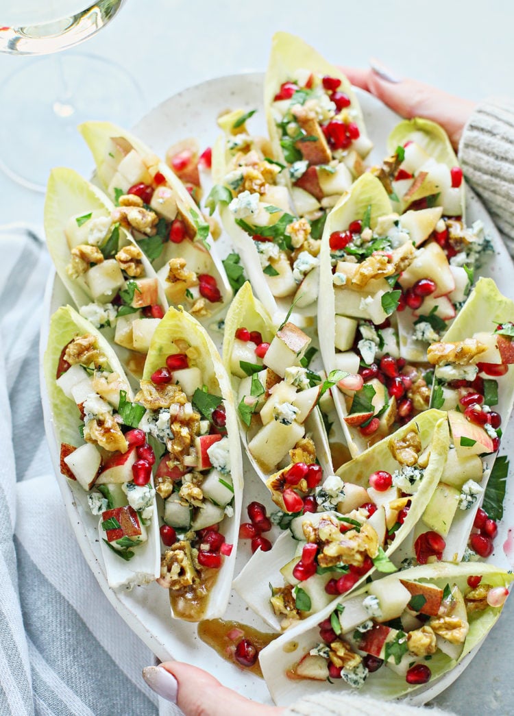 woman holding a platter of endive appetizers