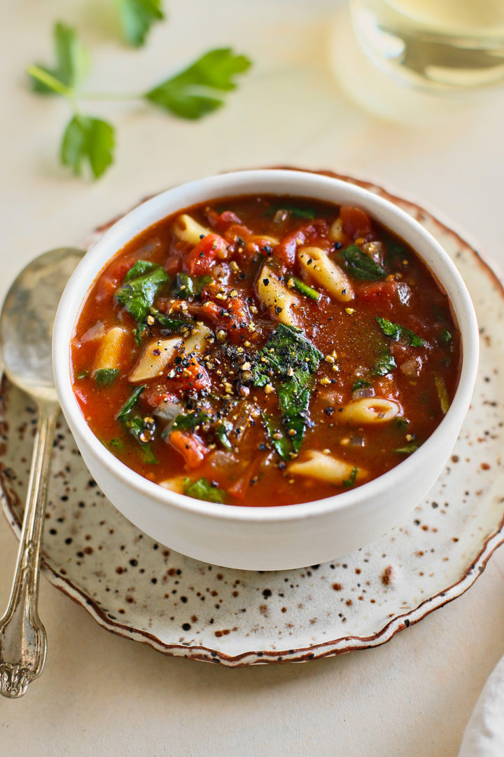 bowl of tomato florentine soup next to a glass of wine