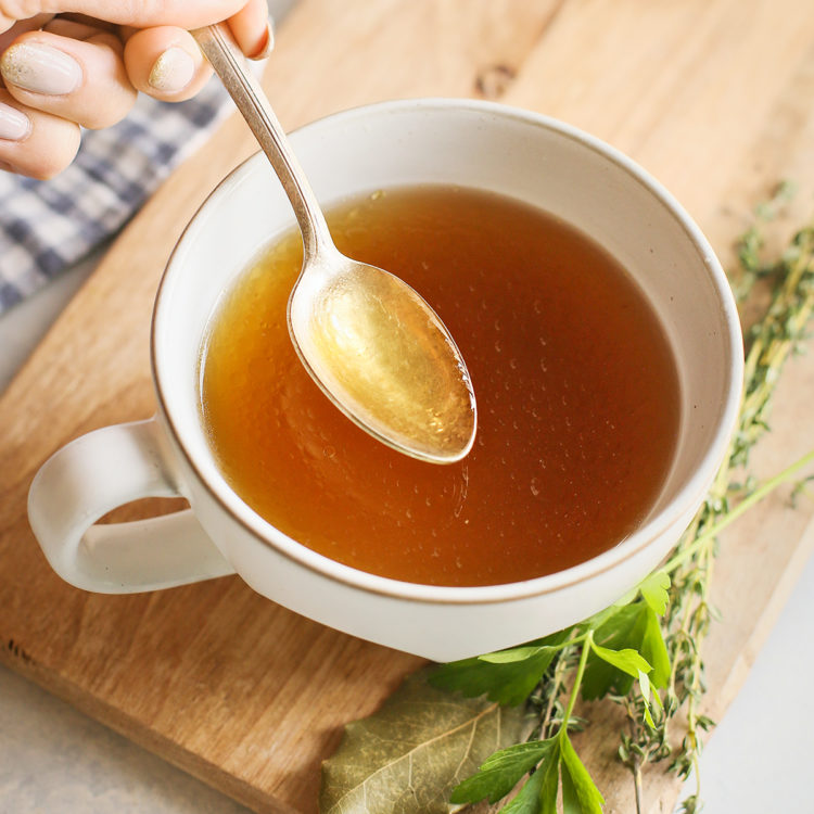 Instant Pot chicken stock in a white mug with a spoon