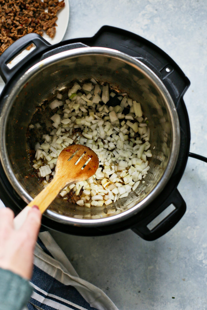 Woman sautéing onion in an instant pot for lentil soup