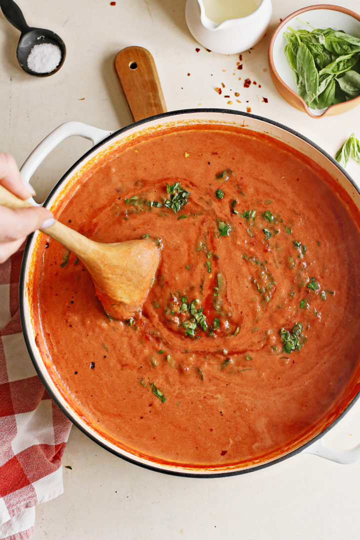 woman stirring sauce to make creamy penne alla vodka recipe 
