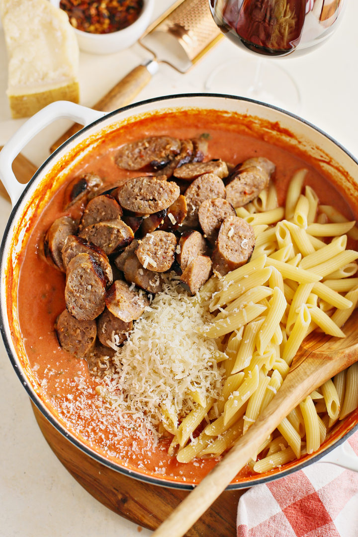 a pan with vodka sauce, penne, italian sausage, and parmesan to make penne alla vodka 
