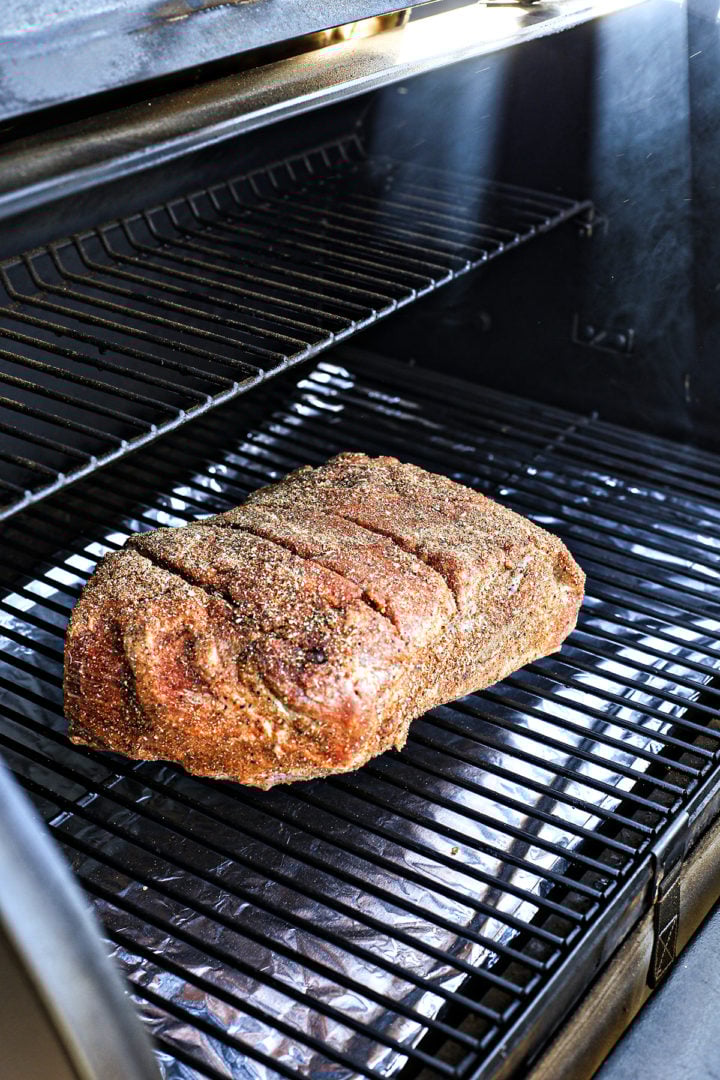 photo with pork shoulder on grill grates showing how to smoke pork shoulder on a traeger